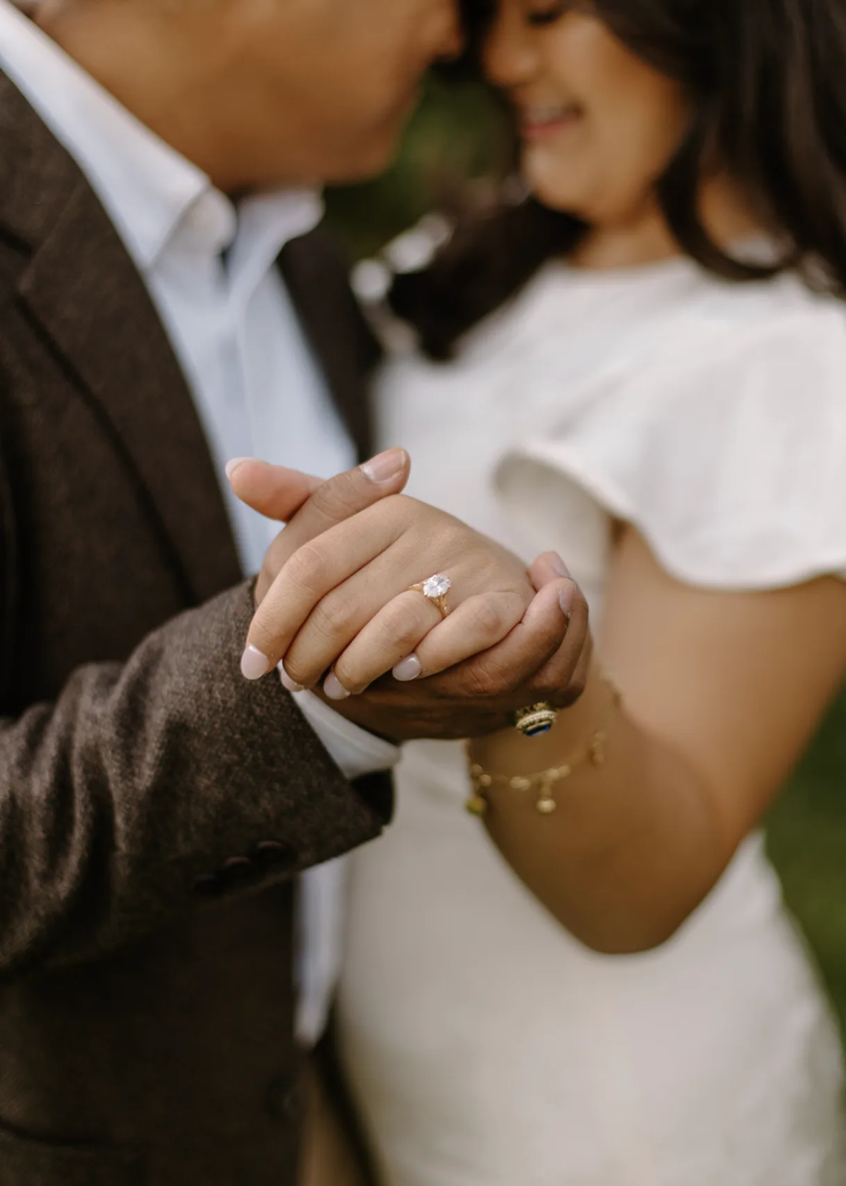Close-up of their joined hands and her engagement ring