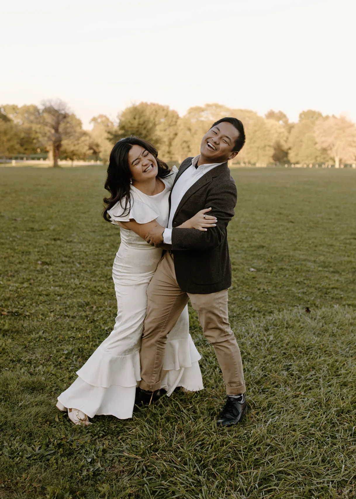A laughing, playful hug in a field at sunset