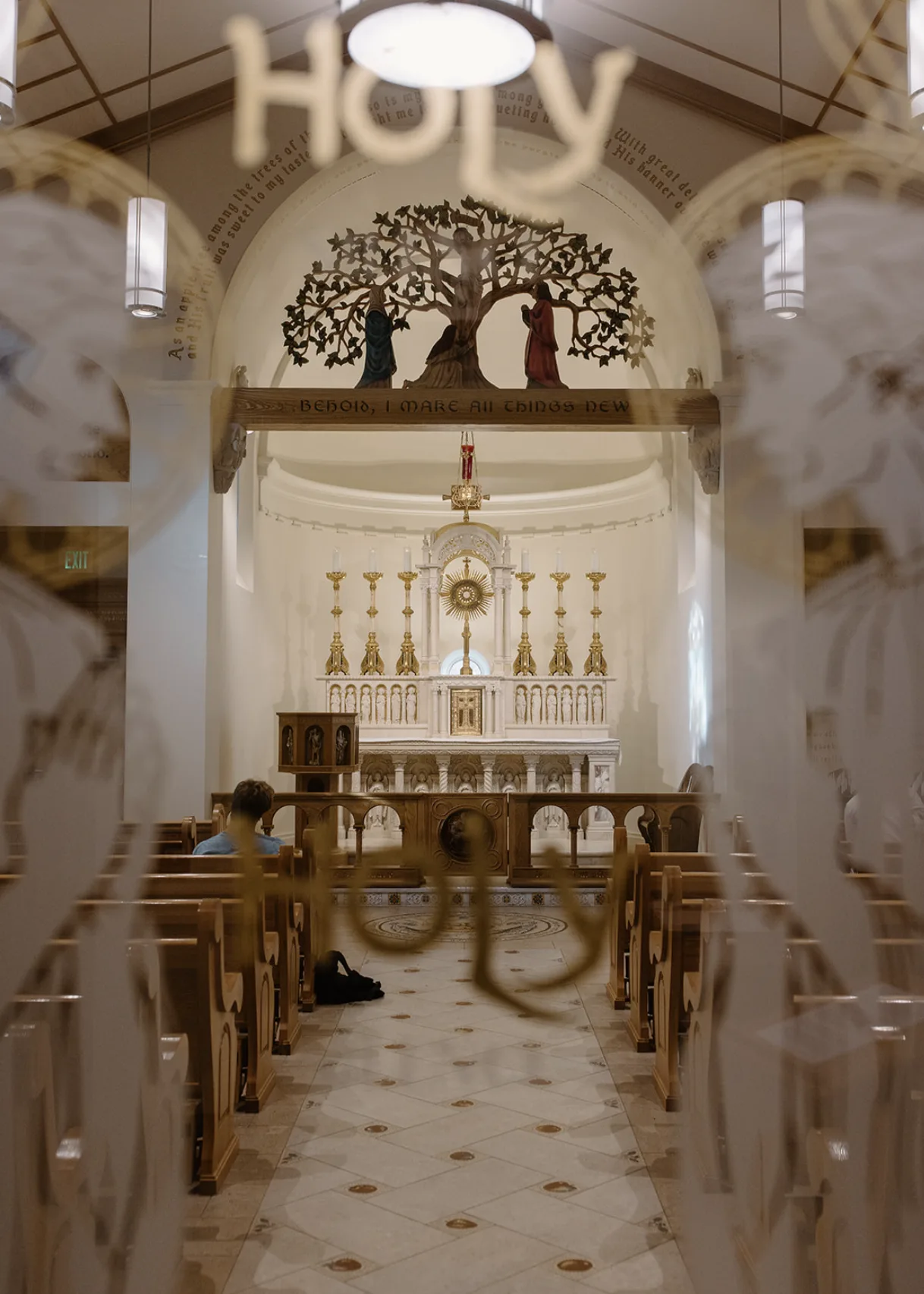 The chapel altar seen through etched glass reading HOLY