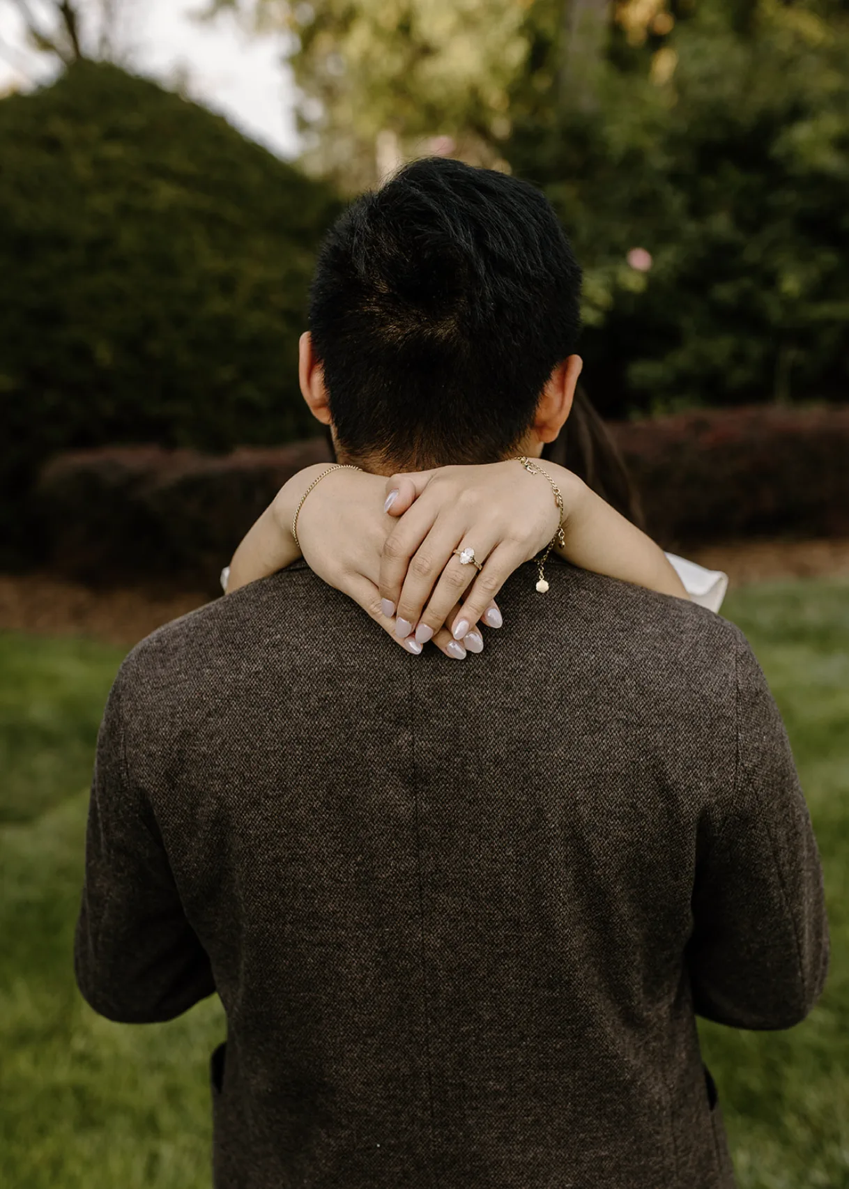 The groom's back to the camera, her ring hand wrapped around his neck