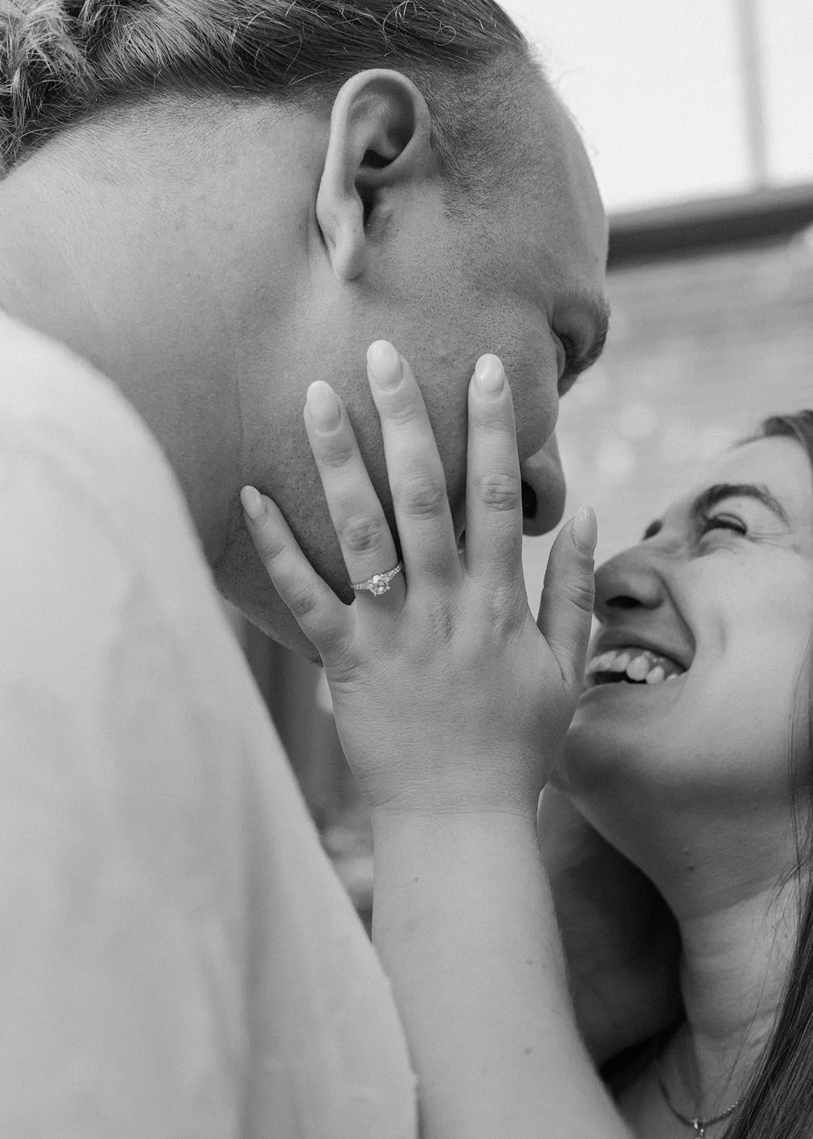 Black-and-white close-up of her hand on his cheek as she laughs