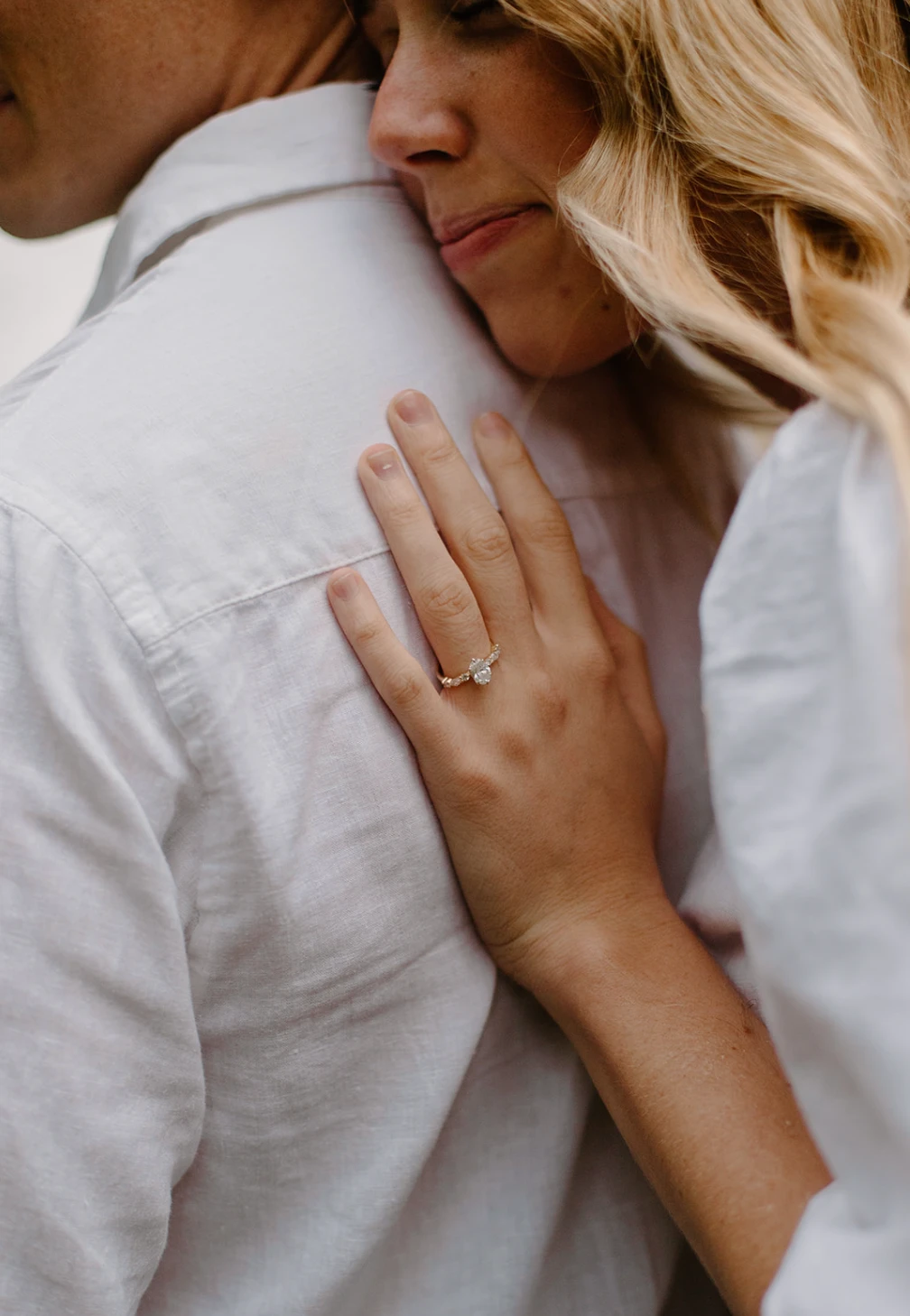 Close-up of her ring hand on his back as she leans into him