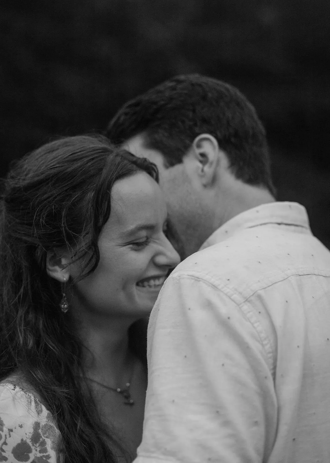 Black-and-white of Grace smiling as John leans into her