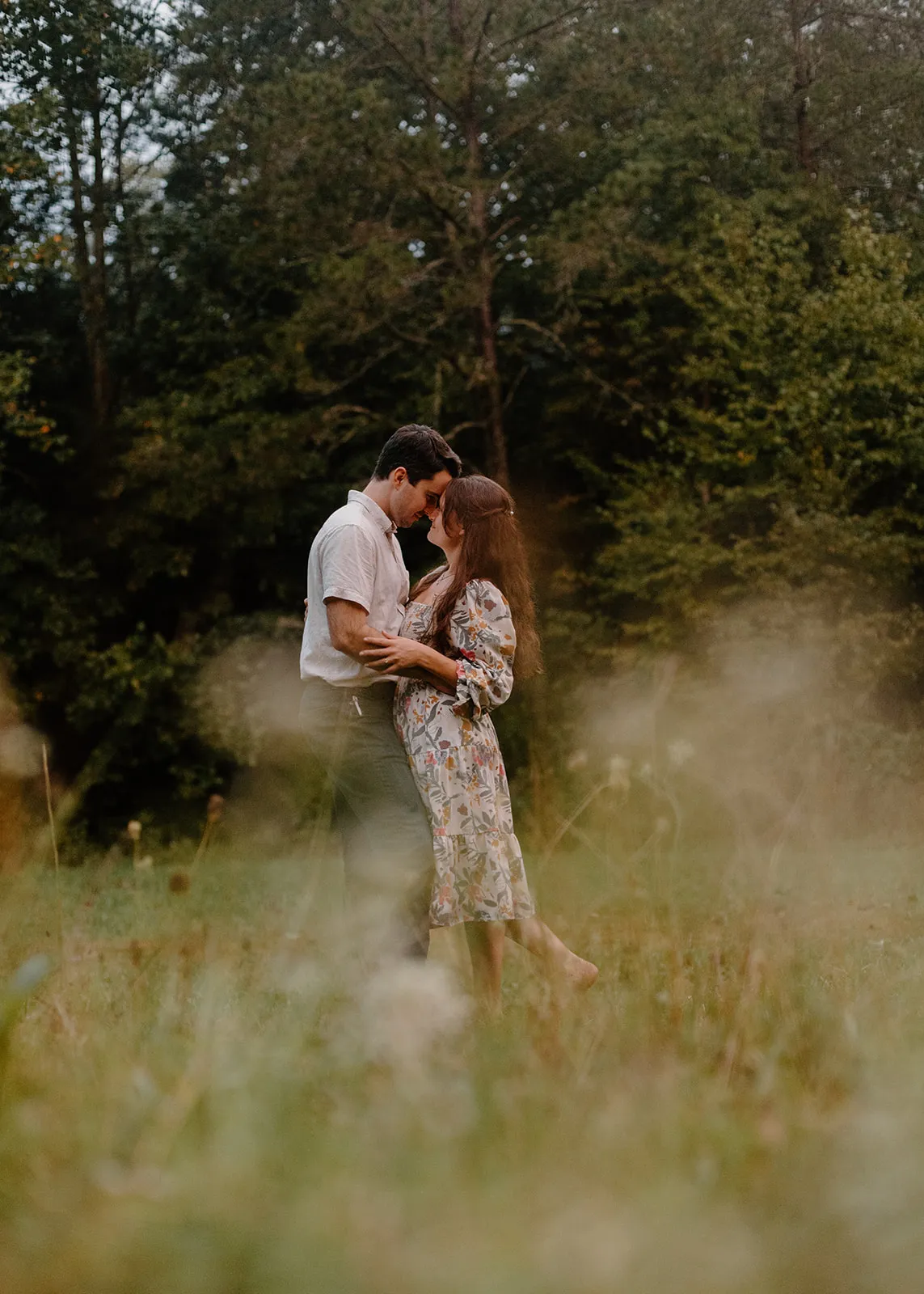 John and Grace forehead to forehead in a tall-grass meadow