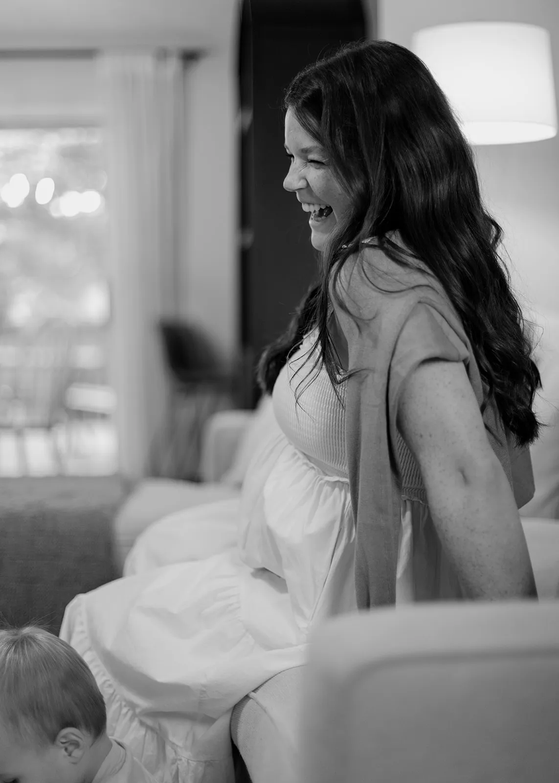 Black-and-white of mom laughing on the arm of the couch